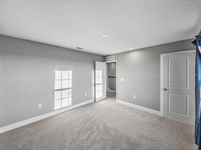 carpeted spare room featuring a textured ceiling