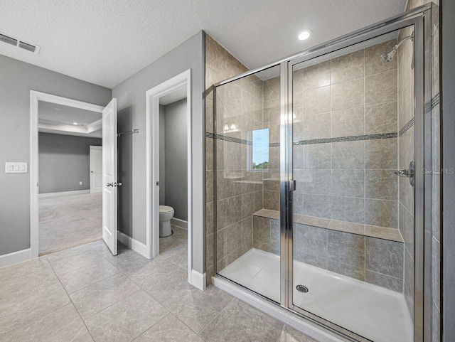 bathroom featuring tile patterned flooring, an enclosed shower, a textured ceiling, and toilet