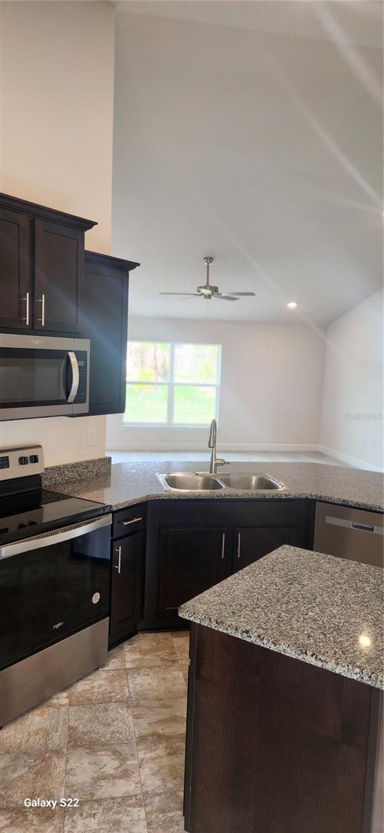 kitchen featuring ceiling fan, appliances with stainless steel finishes, sink, and light stone counters