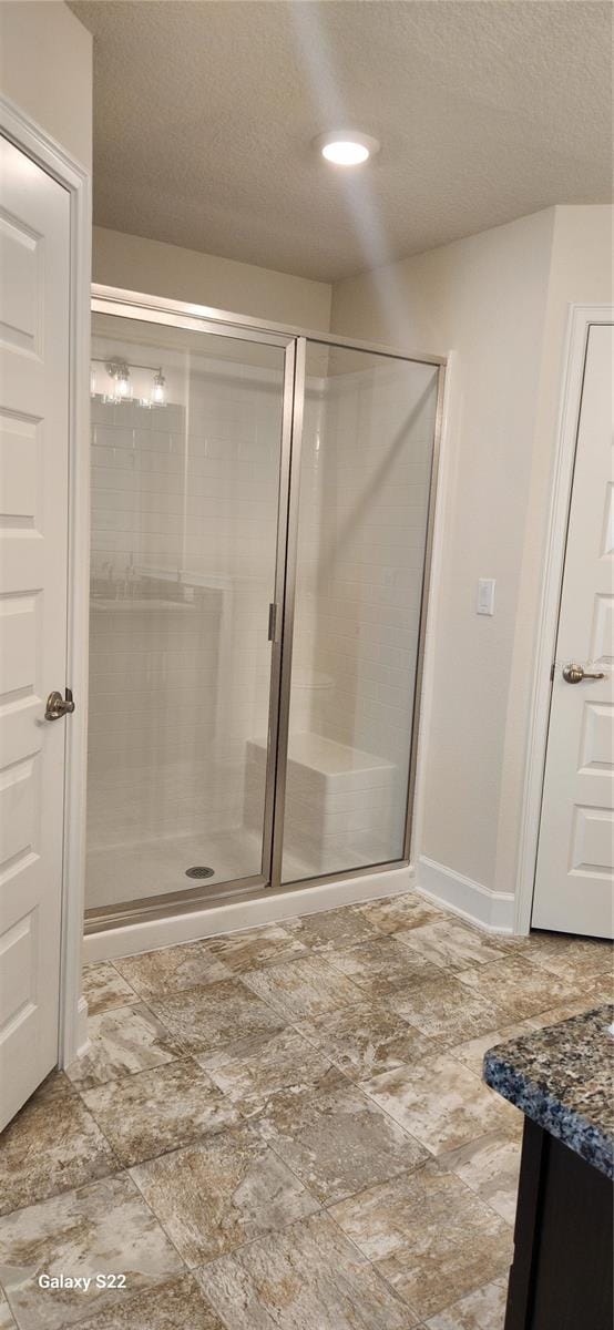 bathroom featuring vanity, a shower with shower door, and a textured ceiling