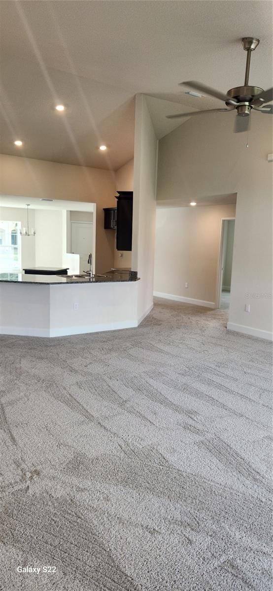 unfurnished living room with sink, vaulted ceiling, a textured ceiling, ceiling fan, and carpet