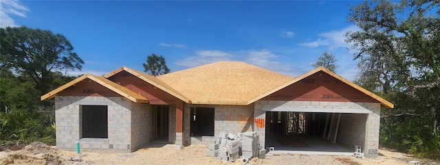 view of front of house featuring a garage, concrete block siding, and a shingled roof