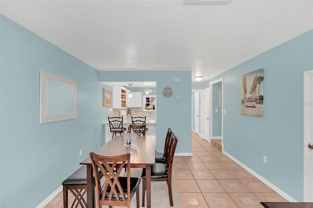 tiled dining area featuring a textured ceiling