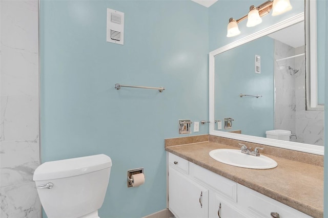 bathroom with tiled shower, vanity, and toilet