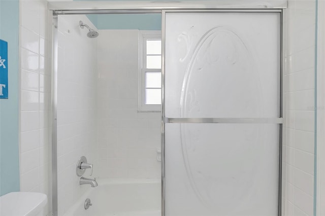 bathroom featuring bath / shower combo with glass door and toilet