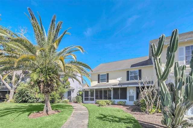 view of front facade with a front yard and a sunroom