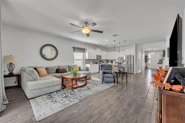 living room with ceiling fan and light wood-type flooring