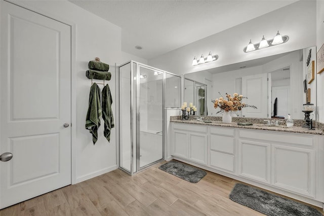 bathroom with hardwood / wood-style flooring, vanity, and a shower with door