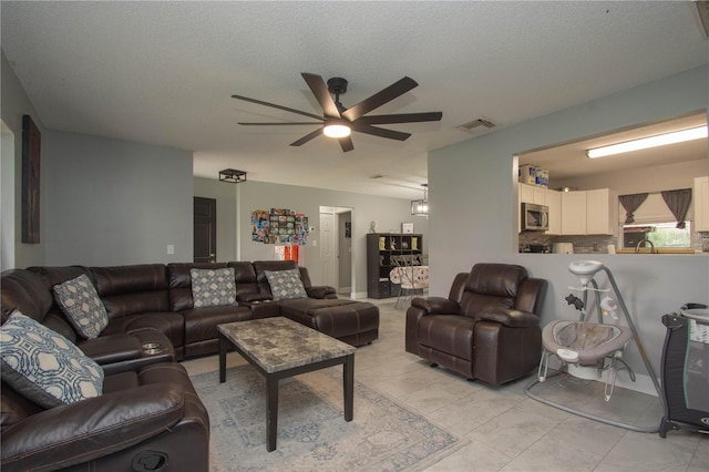 living room with ceiling fan, sink, and a textured ceiling