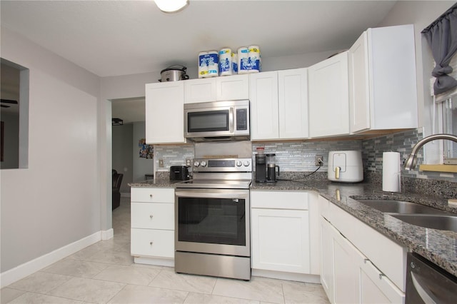 kitchen featuring appliances with stainless steel finishes, sink, dark stone counters, and white cabinets