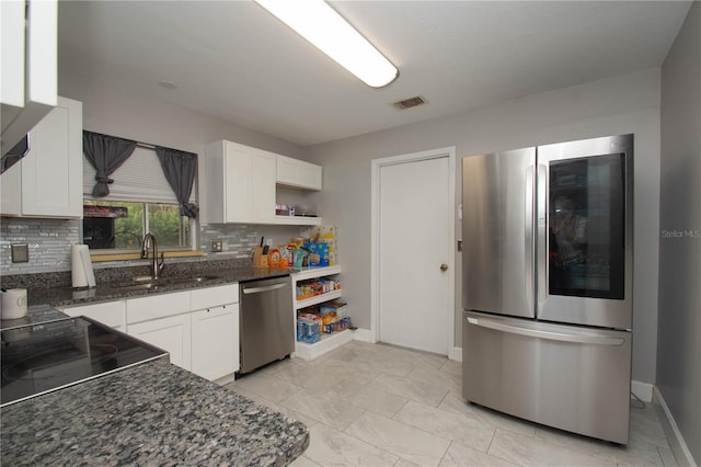 kitchen with stainless steel appliances, white cabinetry, sink, and backsplash