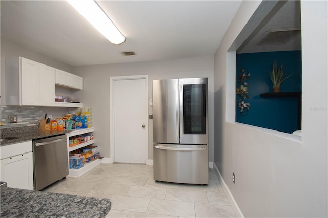 kitchen featuring dark stone countertops, stainless steel appliances, decorative backsplash, and white cabinets