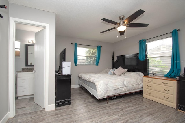 bedroom with ceiling fan, ensuite bath, light hardwood / wood-style floors, and a textured ceiling