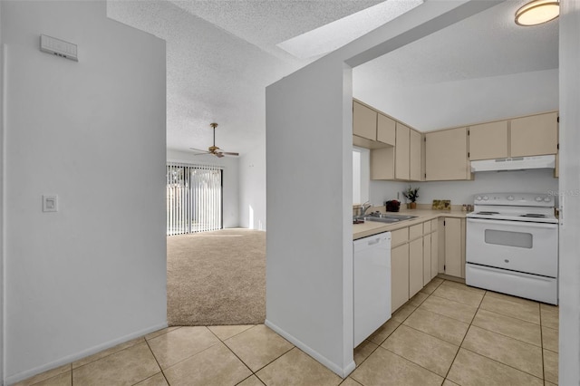 kitchen with sink, a textured ceiling, light tile patterned floors, white appliances, and cream cabinetry