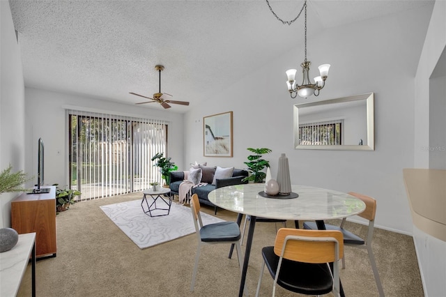 dining space with lofted ceiling, ceiling fan with notable chandelier, carpet floors, and a textured ceiling