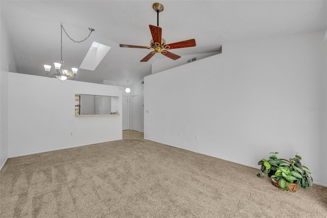 empty room featuring ceiling fan with notable chandelier, carpet floors, and lofted ceiling with skylight