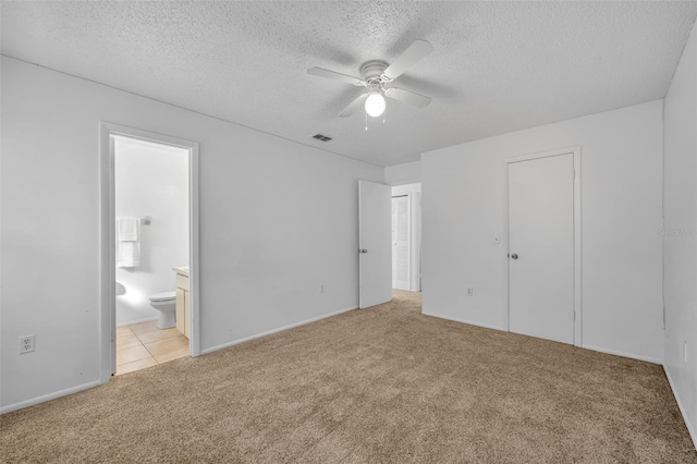 unfurnished bedroom featuring ceiling fan, light colored carpet, ensuite bathroom, and a textured ceiling