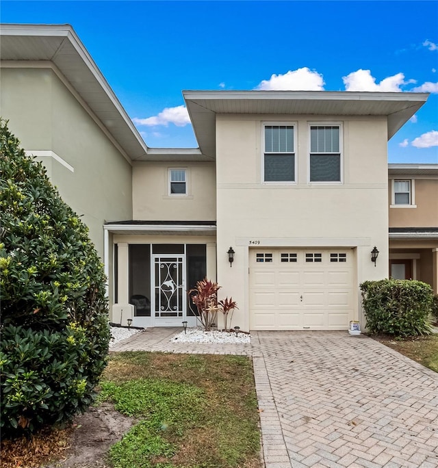 view of front of house featuring a garage, decorative driveway, and stucco siding