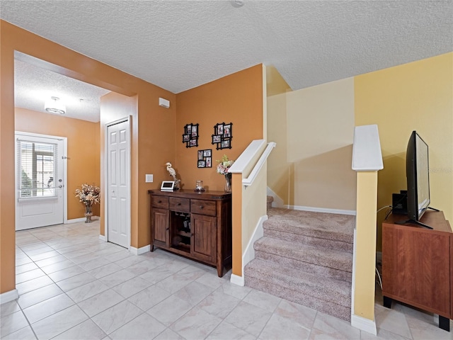 staircase featuring baseboards, a textured ceiling, and tile patterned floors