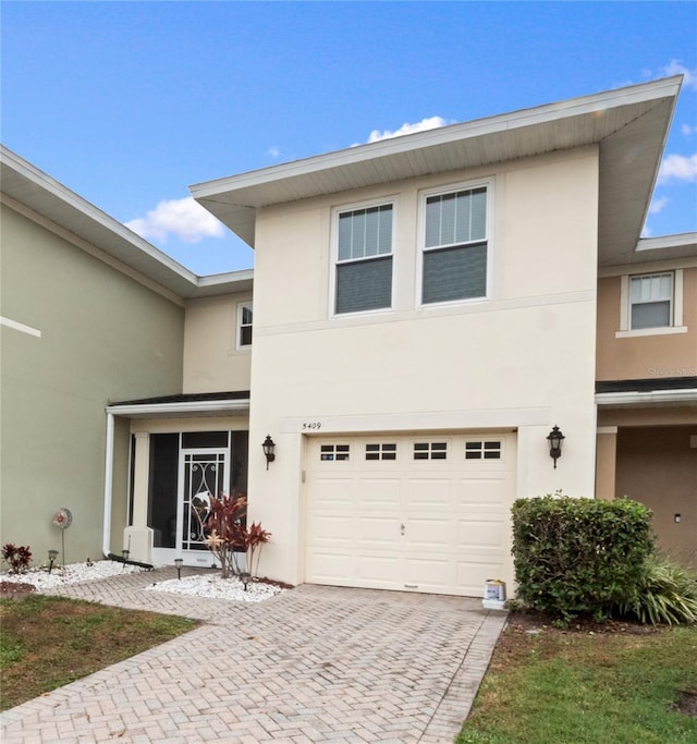view of front of home with decorative driveway, a garage, and stucco siding