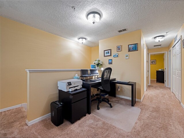 carpeted office with visible vents, a textured ceiling, and baseboards