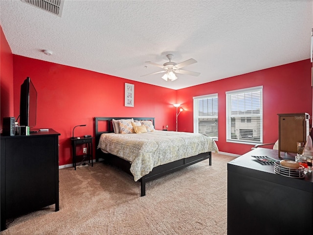 bedroom with ceiling fan, light carpet, a textured ceiling, and visible vents
