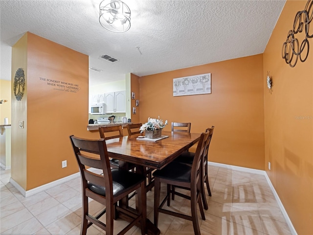 dining space featuring baseboards, light tile patterned flooring, a textured ceiling, and visible vents