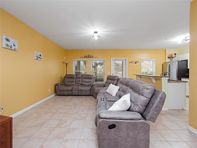 living room featuring light tile patterned floors, baseboards, and a textured ceiling