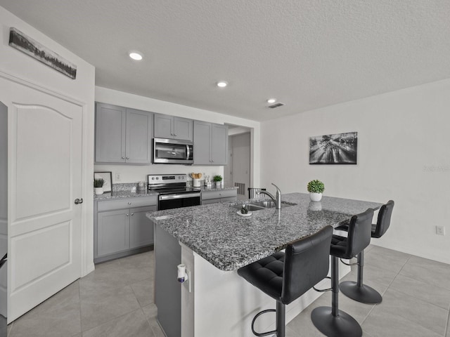 kitchen featuring appliances with stainless steel finishes, sink, a kitchen island with sink, and a breakfast bar