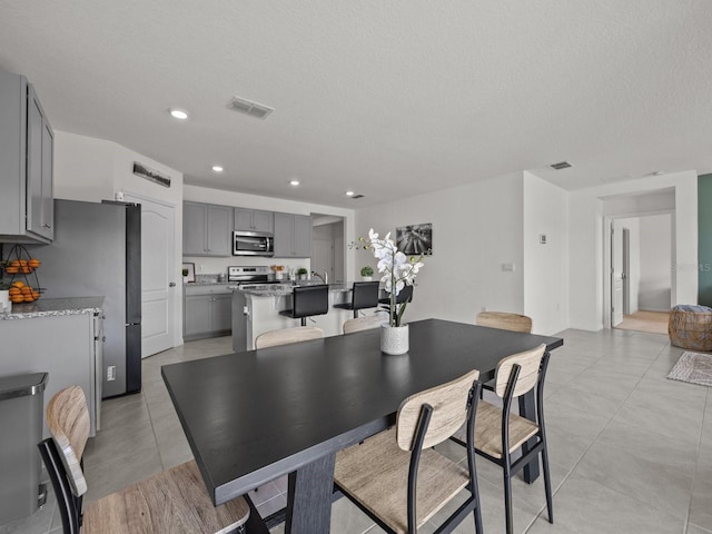 dining area with a textured ceiling and light tile patterned floors