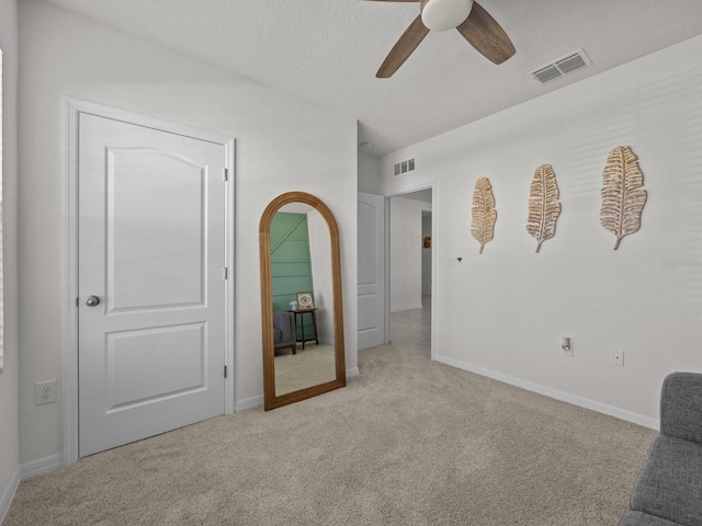 carpeted empty room with ceiling fan and a textured ceiling