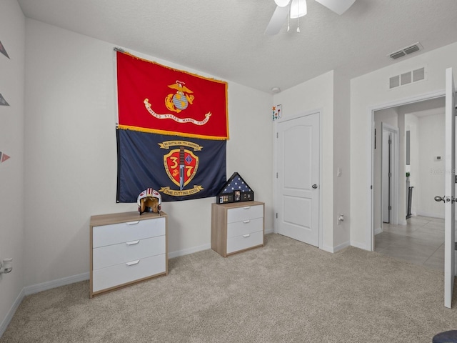 unfurnished bedroom featuring ceiling fan, light colored carpet, and a textured ceiling