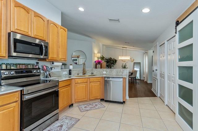 kitchen featuring sink, light tile patterned floors, appliances with stainless steel finishes, hanging light fixtures, and a chandelier