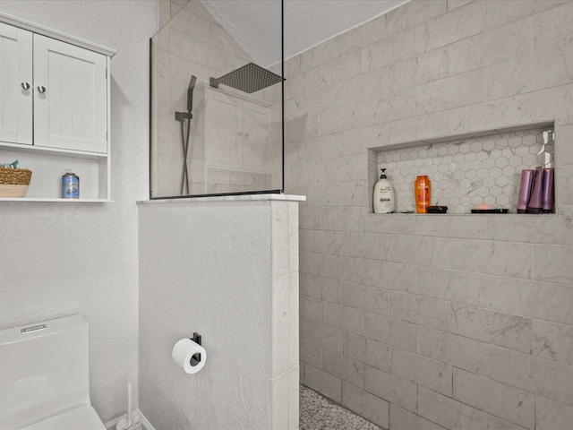 bathroom featuring tiled shower and toilet