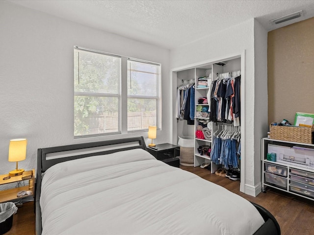 bedroom with dark wood-type flooring, a textured ceiling, and a closet