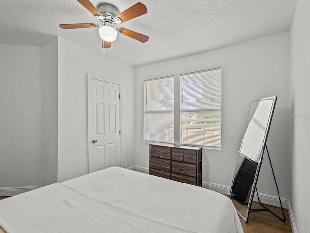 bedroom with ceiling fan, hardwood / wood-style flooring, and a textured ceiling