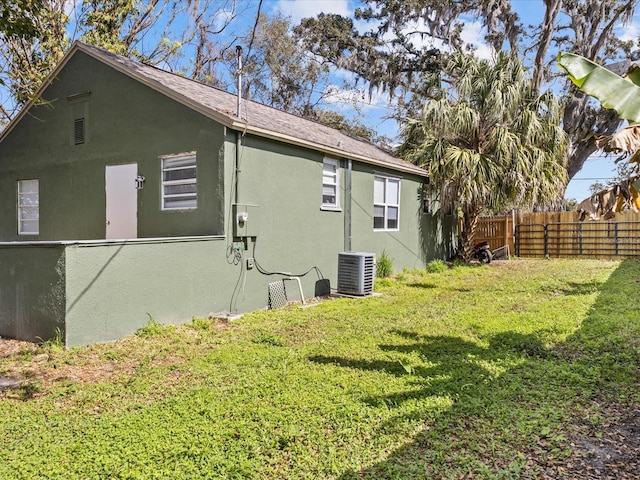 view of side of property with central AC unit and a yard