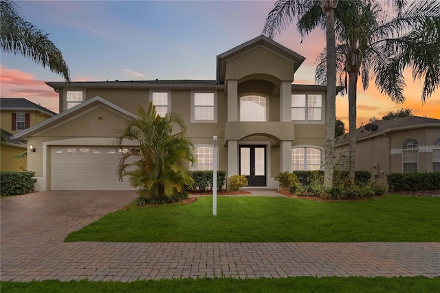 mediterranean / spanish home with a garage, french doors, and a lawn