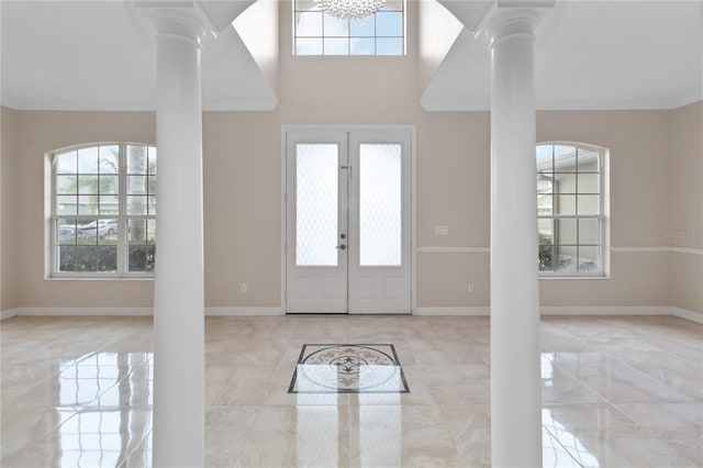 foyer entrance with decorative columns, ornamental molding, and a healthy amount of sunlight