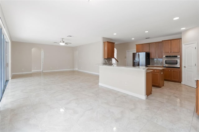 kitchen with stainless steel appliances, tasteful backsplash, a center island, and ceiling fan