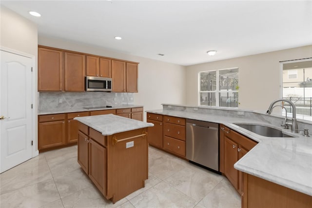 kitchen featuring sink, decorative backsplash, a center island, light stone counters, and stainless steel appliances