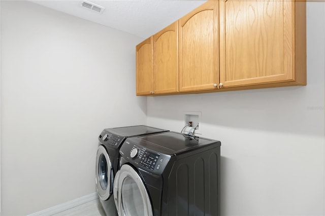 washroom with cabinets and washing machine and dryer