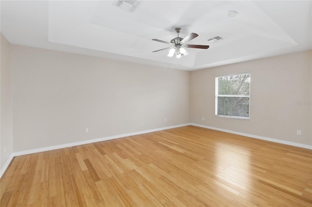 spare room featuring a tray ceiling, light hardwood / wood-style floors, and ceiling fan