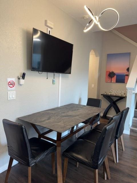 dining area featuring an inviting chandelier, vaulted ceiling, and dark hardwood / wood-style floors