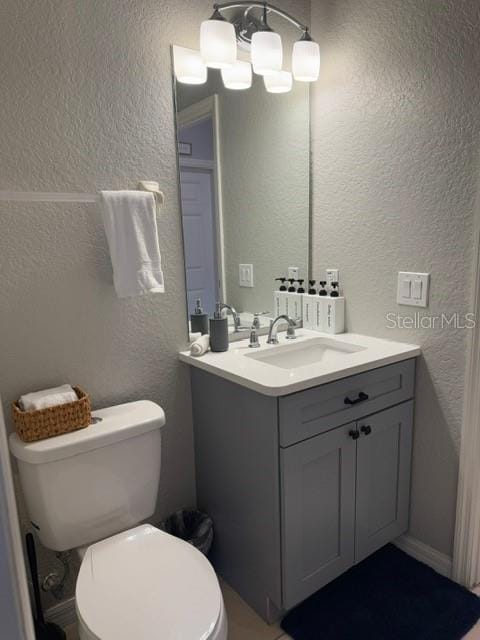 bathroom with vanity, toilet, and a notable chandelier