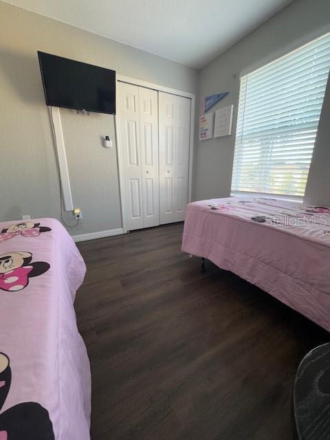 bedroom featuring a closet, baseboards, and dark wood-type flooring