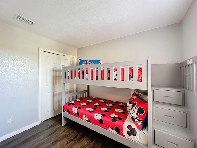 bedroom featuring a closet, dark hardwood / wood-style floors, and a textured ceiling