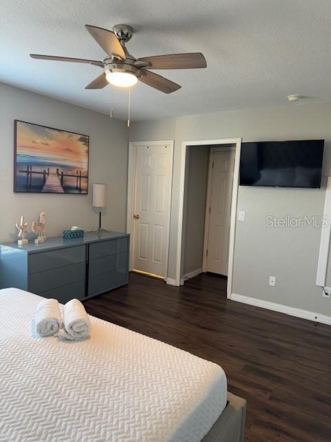 bedroom with dark wood-type flooring, ceiling fan, and a textured ceiling