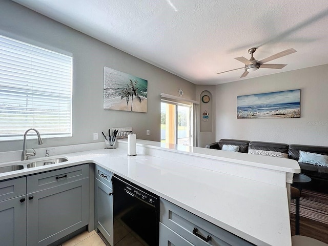 kitchen with a peninsula, a sink, gray cabinetry, black dishwasher, and a kitchen bar