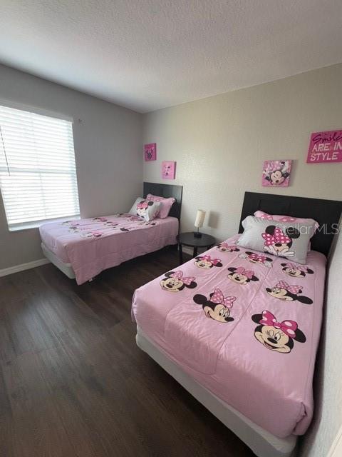 bedroom featuring a textured ceiling, baseboards, and wood finished floors